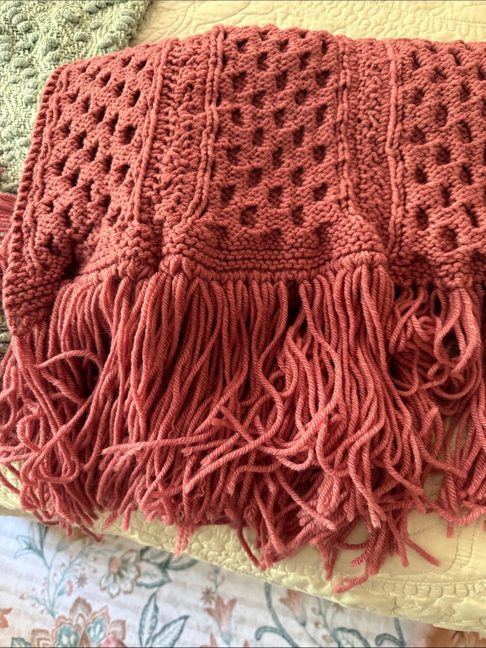 Handmade dusty rose crochet wrap with openwork lattice pattern and fringed ends,